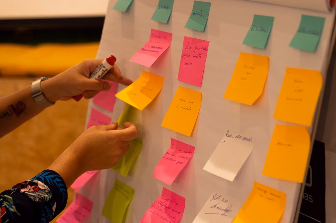 Participante organiza ideias e percepções em um painel colaborativo durante uma atividade dos Hubs de Cidadania Ativa.
