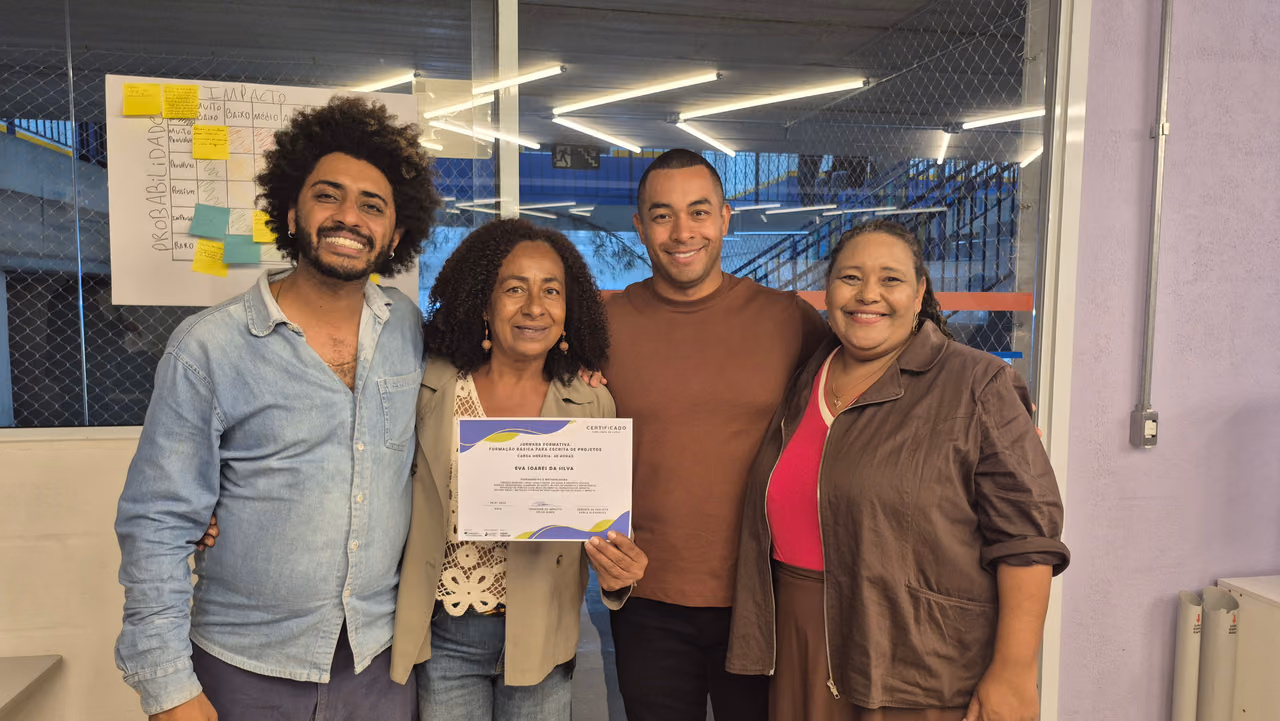 Karla e a equipe do Hub, entregando o certificado para uma das participantes da jornada formativa.