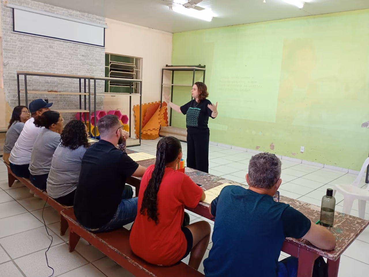 Participantes de uma atividade colaborativa registram ideias em folhas de papel, utilizando materiais de escrita para desenvolver propostas e organizar pensamentos.